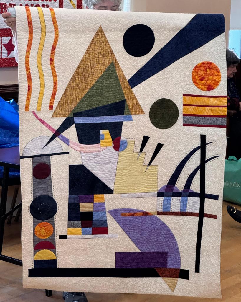 A Kandinsky inspired piece with geometric pieces on a pale background.
