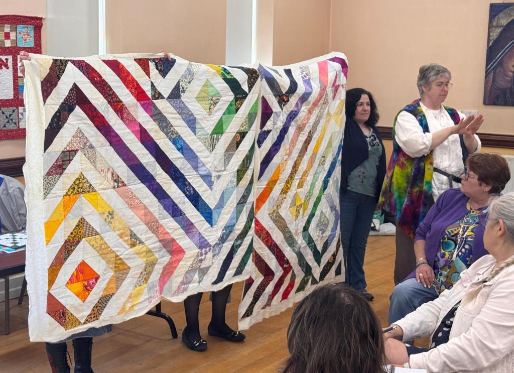 Two rainbow hued quilts made from half square triangles and pale fabric, set in diagonal lines